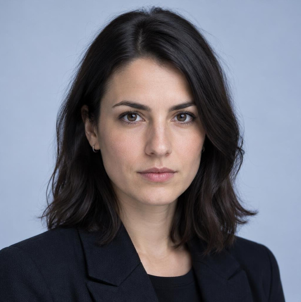 Woman with dark hair and blue-lit background looking at camera