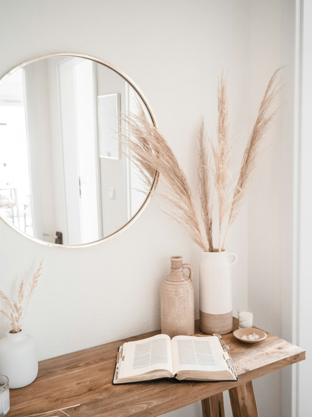 Stylish interior with dried pampas grass vase and round wooden mirror